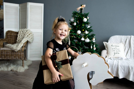 幸福微笑的小女孩拿着礼物盒坐在圣诞树上