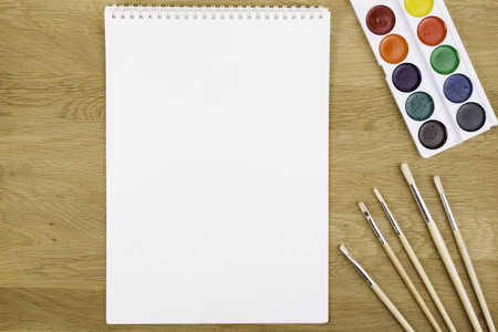 水彩颜料 画笔和空白白色纸张上木制的背景。顶视图