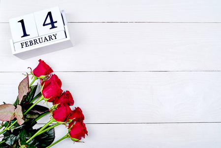 白色木制情人节背景与红色玫瑰花束和木块日历与日期2月14日，复制空间为文本。节日贺卡模型。爱的概念，俯视，平躺