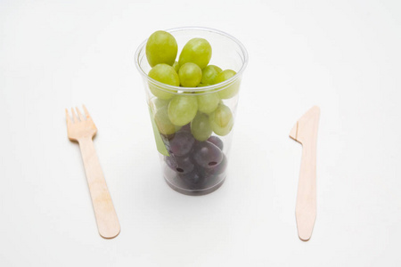 白色背景带刀叉的快餐容器中的葡萄