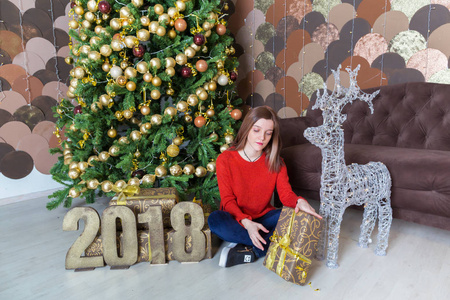 一个年轻漂亮的女孩在圣诞树旁，带着礼物2018年