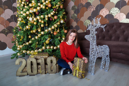 一个年轻漂亮的女孩在圣诞树旁，带着礼物2018年