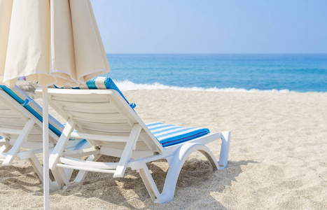 太阳伞和贵妃椅在海边。热带度假胜地的白沙和大海。海滩度假的概念。放松和度假