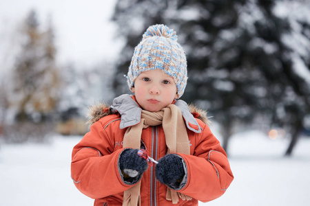 男孩在编织的冬天帽子与糖果糖果