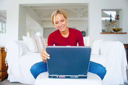 女人在沙发上用笔记本电脑