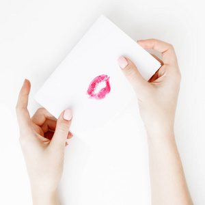 平躺。顶部视图。在圣情人节写情书的女孩的手。手工明信片与红唇形状的身影。妇女画亲吻在明信片为2月14日假日庆祝