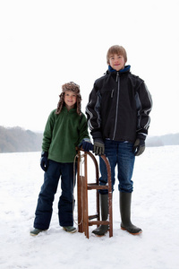 两个男孩站在雪橇旁边