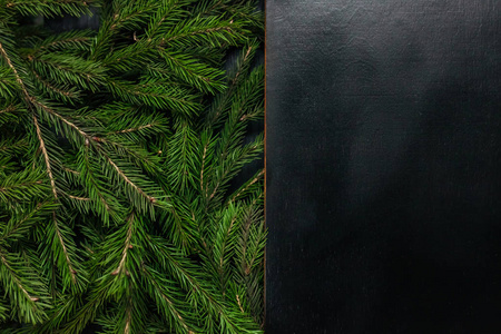 新鲜的冷杉枝孤立在黑色背景上。 从顶部看。 圣诞设计木制背景。 美丽的杉杉