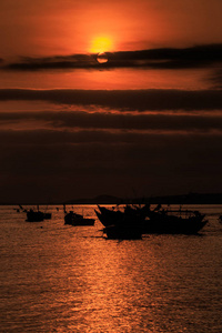 越南渔船在夕阳余晖下，迎着灿烂的太阳盘在海上剪影