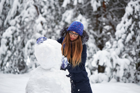 冬天的乐趣。戴着针织帽子的女孩造型雪人