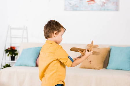 小可爱的小男孩在家玩木玩具飞机