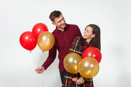 美丽的高加索年轻幸福的微笑情侣在爱。女人和男人穿着格子花纹的衣服, 带着红色黄色的气球, 庆祝生日, 在白色背景上隔绝。假日