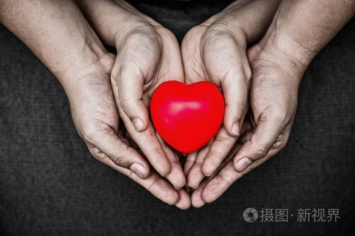 女人和男人手中的小心脏年轻的男人和女人在他们的手掌上抱着一颗红色
