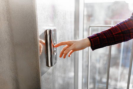 拇指按下电梯按钮,一只手伸出按钮,等待电梯按钮的女孩开始隔离照片