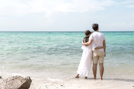 年轻快乐的跨种族夫妇在海滩上互相拥抱. 亚洲女人高加索男人.