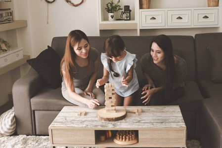 两个女人和女儿在客厅玩拼图游戏。 家庭乐趣时间概念。