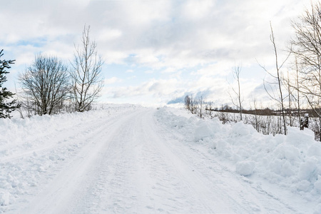 一条乡村雪路, 路边有小雪堆, 路边长树, 冬天在阳光明媚的日子里