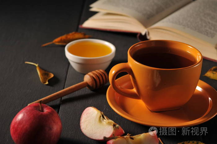 秋季静物杯茶,蜂蜜和桌子上的书