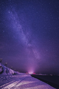 夜晚的风景，五颜六色的银河和黄色的灯光在山上。 夏天有小山的星空。 美丽的宇宙。 空间背景