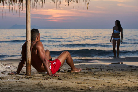 蜜月浪漫的情侣恋爱中的情侣站在沙滩上橙色的日落背景快乐的年轻夫妇牵着手在旅行假期里享受海洋日出