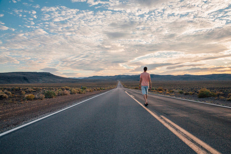 年轻人走在美国死亡谷的无尽的路上.照片