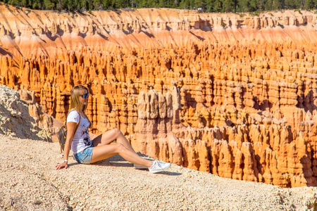 探索布莱斯峡谷的年轻女孩。 沿着橙色的悬崖徒步旅行。 美丽的自然。