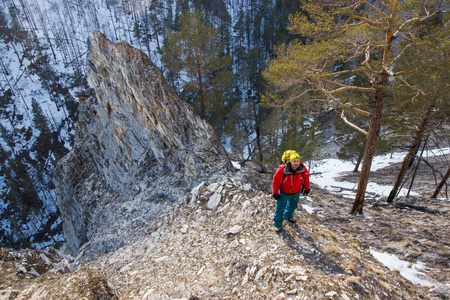 背着背包的人站在岩石的斜坡上，脚上有树，俄罗斯贝加尔湖