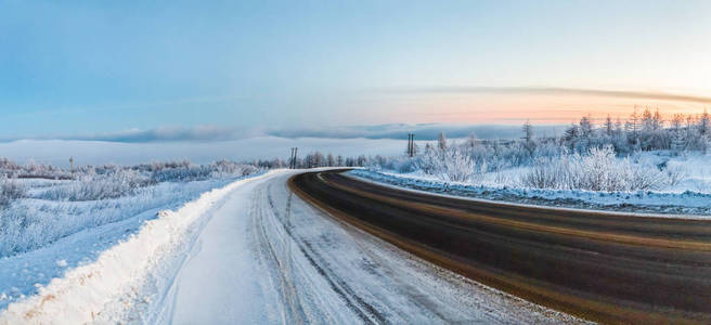 俄罗斯马加丹日落时美丽的冬季道路和雪景摄影图
