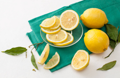 一束柠檬, 叶子和柠檬片放在白色的桌子上