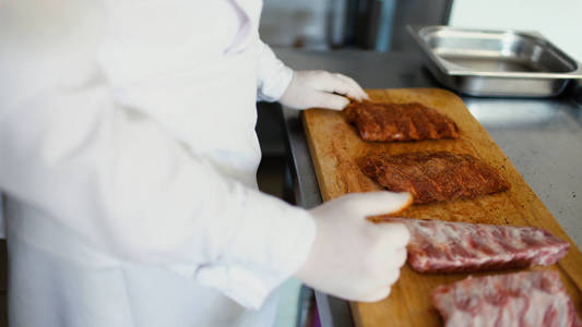 特写的专业厨师人准备香料在餐厅厨房砧板上的肉排骨
