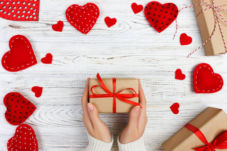 女孩手给情人节礼物盒子里有一颗红色的心在一张白色的旧木桌上。情人节