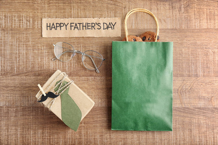 礼品盒带饼干的纸袋和木制背景的眼镜。父亲节作文