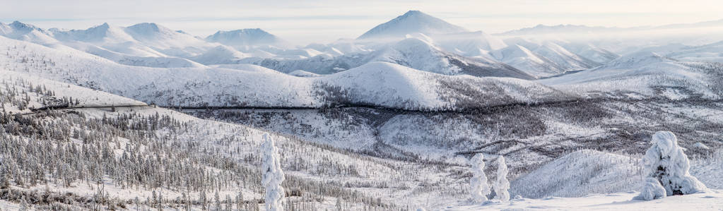 美丽的白雪覆盖冬天的道路和树木在白雪覆盖的山脉，科里马公路，俄罗斯联邦