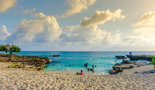 s Barcadere beach in the Caribbean at sunset and people in the w