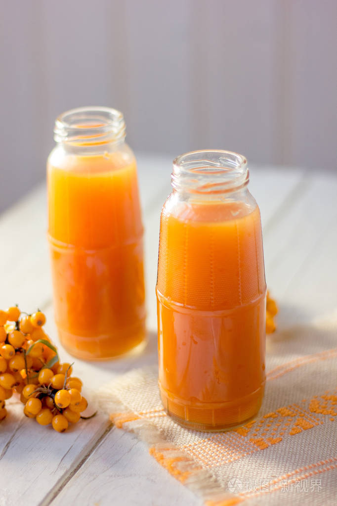 健康饮料沙棘汁在木桌上的玻璃瓶中