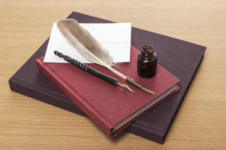 羽毛钢笔墨水和木桌上的书。