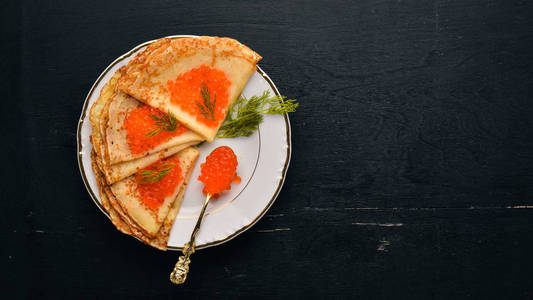 盘子里放着红鱼子酱的煎饼。在木制背景上。上景。免费的文本空间。