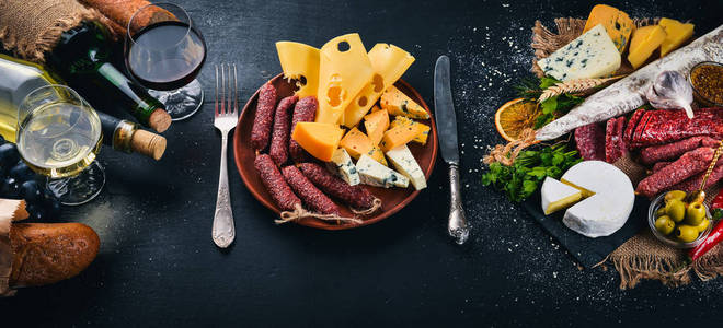 木制背景上的一瓶葡萄酒奶酪和传统香肠。布里奶酪，蓝色奶酪，戈贡佐拉，福伊特，萨拉米。免费的文本空间。上景。