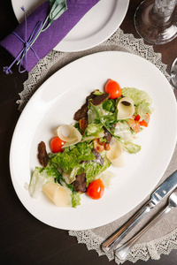 沙拉的顶部视图，配上朱古拉牛肉樱桃西红柿和奶酪，配上餐具和餐巾纸。