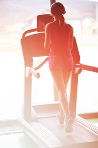 女孩在跑步机上跑步。 健身房里活跃的女孩在跑步机上跑步。 跑步机上的运动员有氧运动。