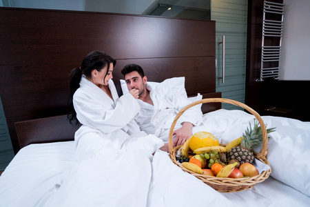 夫妇俩在床上放松，享受水果篮的乐趣。
