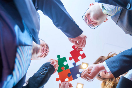团队代表一群商业人士组装拼图,代表现代办公室的团队支持和帮助理念