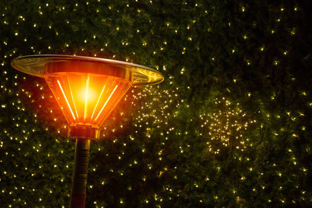 温暖在寒冷的夜晚与加热器塔在圣诞节轻装饰公园。