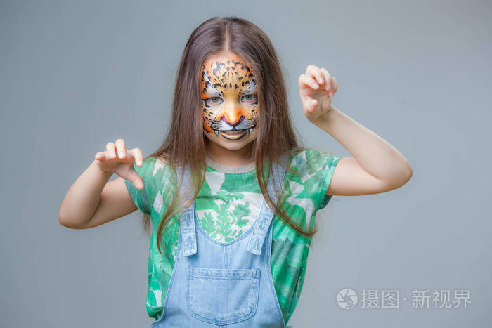 一个小女孩的肖像在她的脸上的灰色背景下画的老虎
