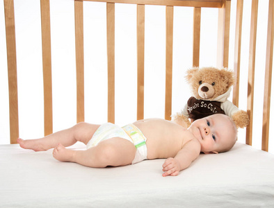 婴儿婴儿女婴躺在床上与泰迪熊尿布