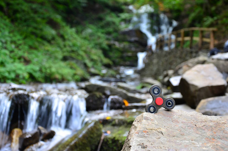 木制旋转器躺在岩石上，背景是一条小瀑布和一条河。