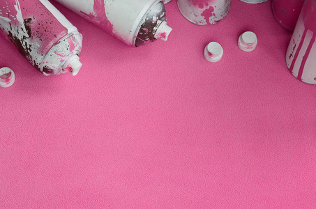 一些使用过的粉红色气溶胶喷雾罐和带有油漆滴的喷嘴躺在柔软而毛茸茸的浅粉红色羊毛织物的毯子上。 经典的女性设计颜色。 涂鸦流氓概念