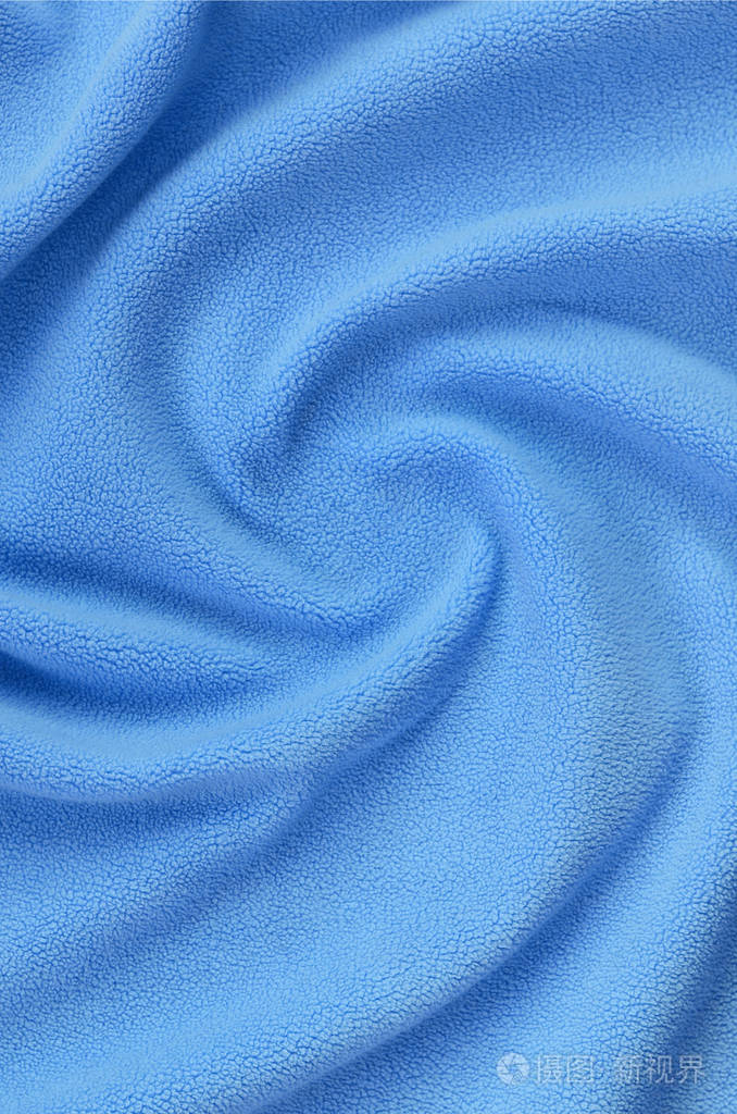 毛茸茸的蓝色羊毛织物的毯子. 背景浅蓝色软毛绒材料,有很多浮雕褶皱