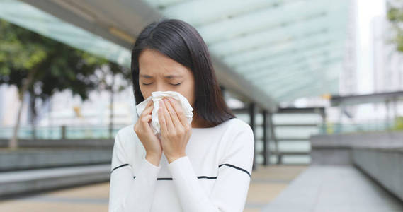 年轻女子在户外打喷嚏