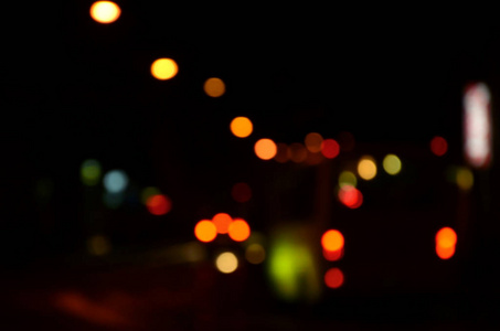 道路上交通的模糊夜景。 用发光前照灯旅行的汽车的离焦图像。 波克艺术